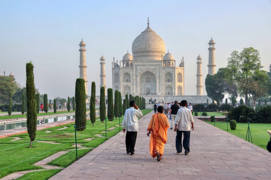 The Taj Mahal, and trees, with people walking towards the building/