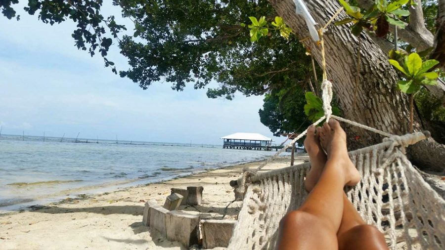 Image of a person's legs and feet relaxing on a hammock on the beach