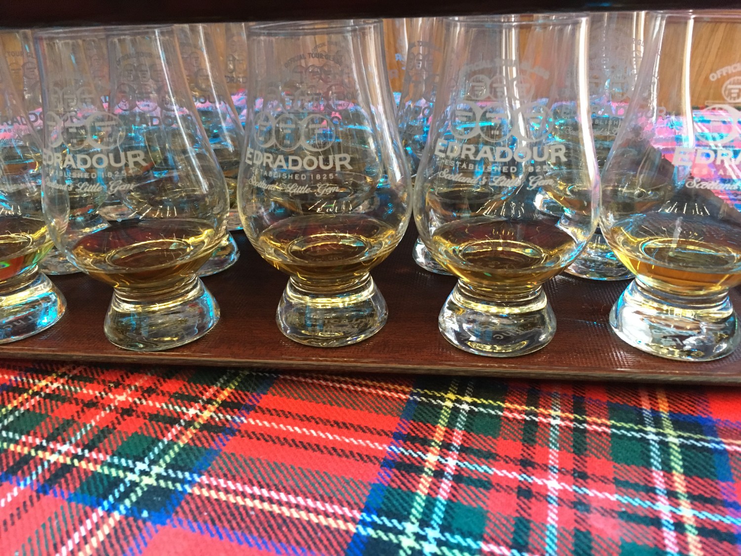 A tray full of drams of whisky resting on tartan at Edradour Distillery in Pitlochry, Scotland