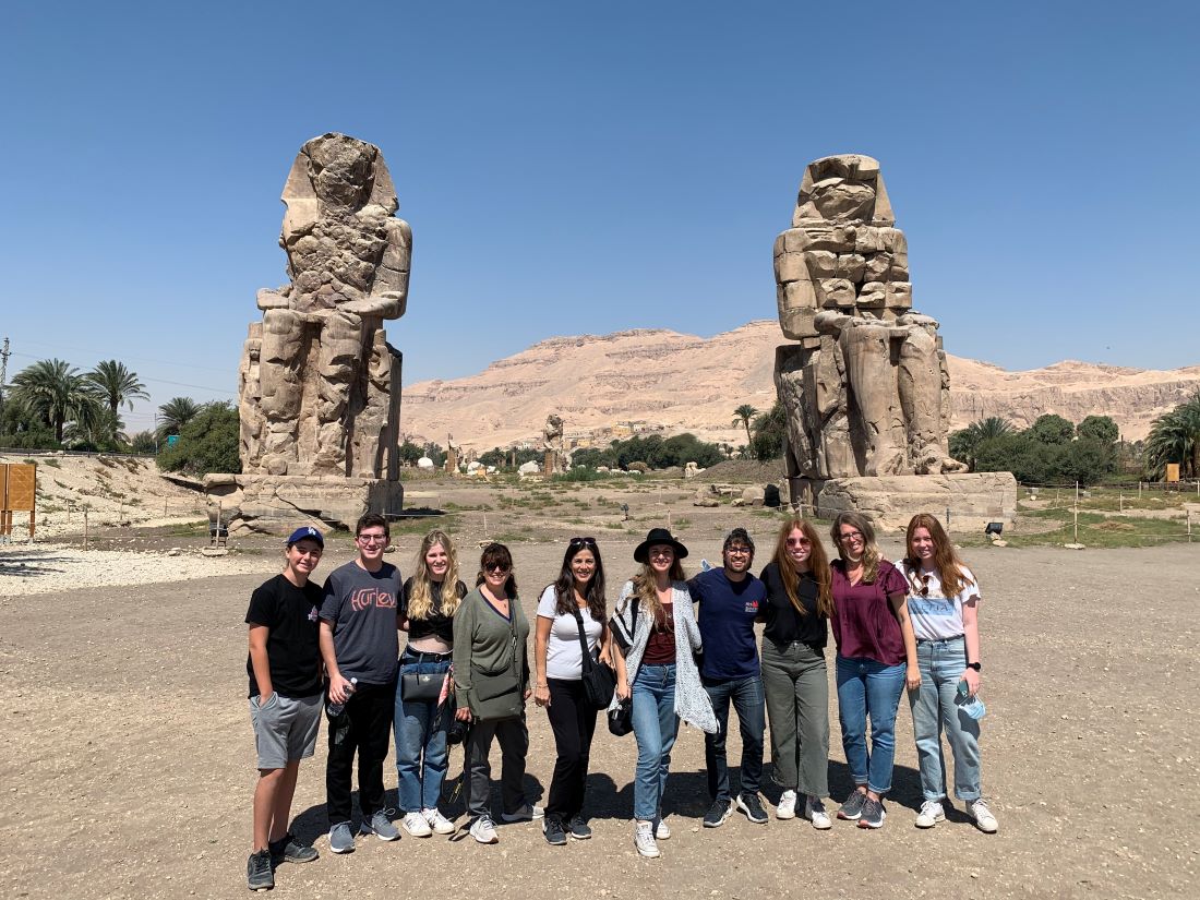 A group of teenagers posing in front of ancient ruins