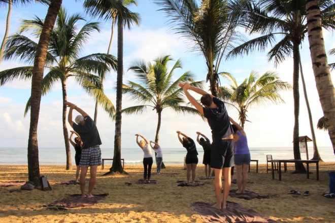 People stretching during a yoga class on the beach at a resort in Mexico