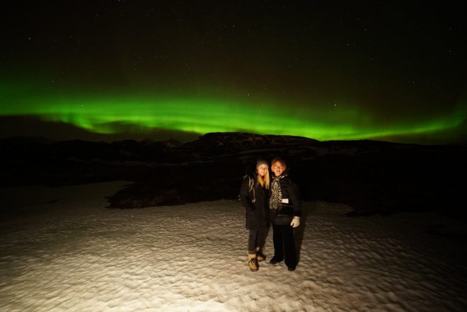 Northern Lights in Iceland with Laura Harris and her mom posing in front of a strong display