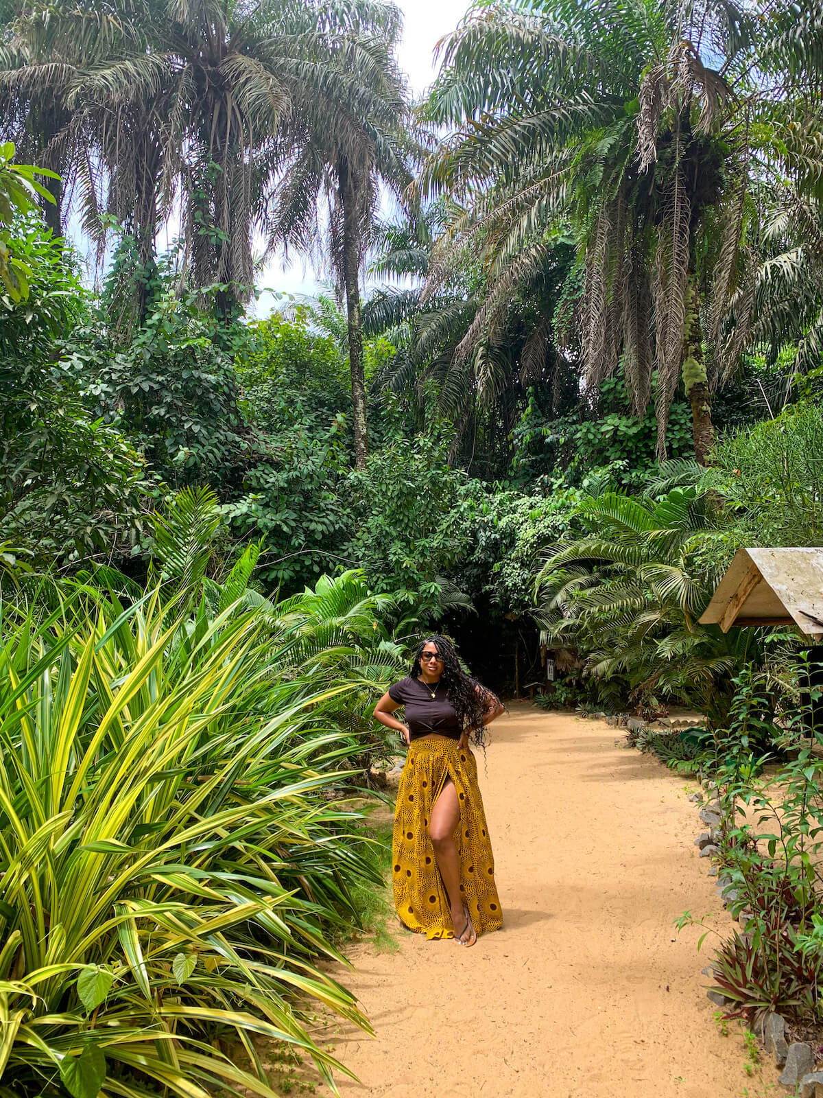 Royda Philimena Urey standing on a sand path amidst jungle 