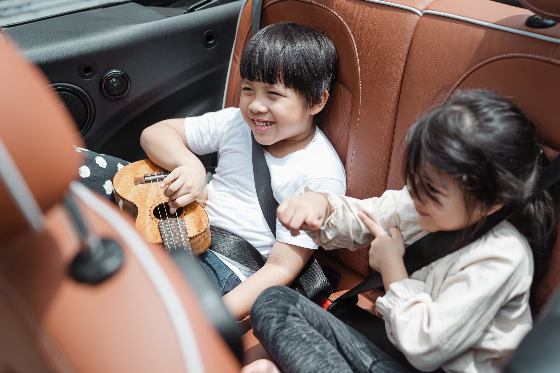 happy kids traveling in car - tips for road trips with family or friends