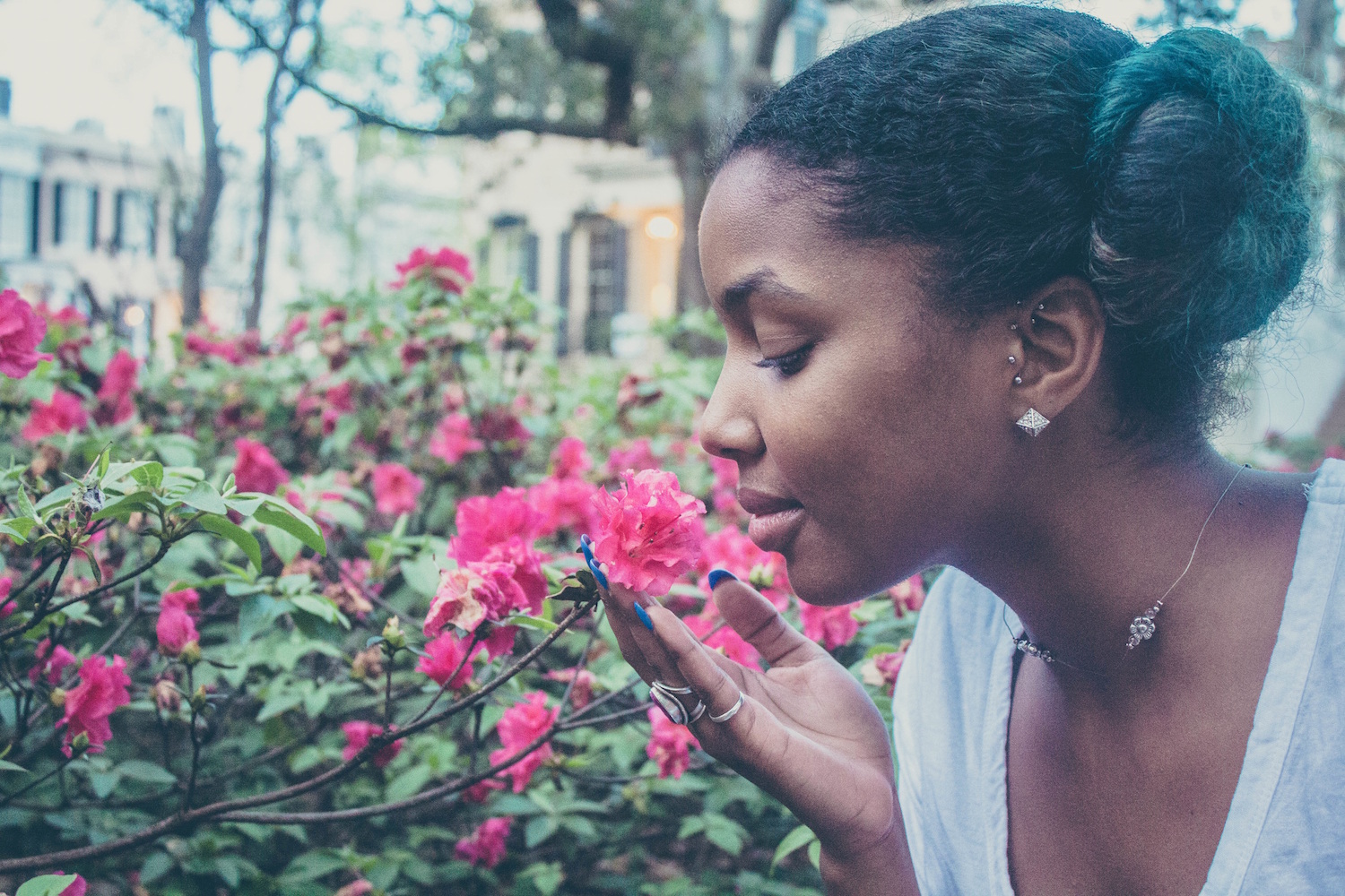 Close up image of a Black woman smelling a pink flower