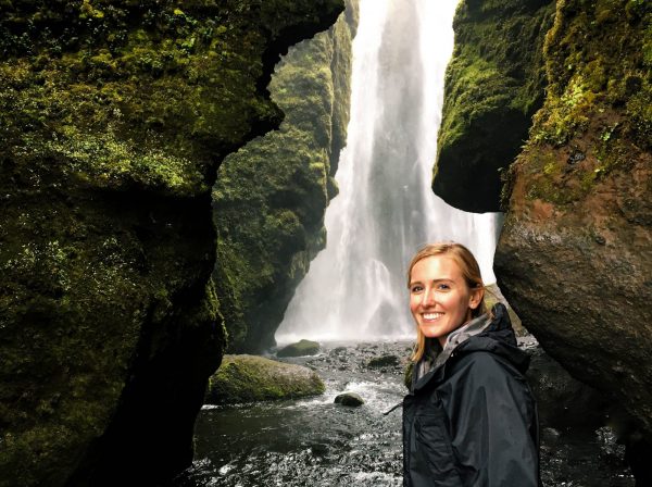 Woman in raincoat standing in front of waterfall