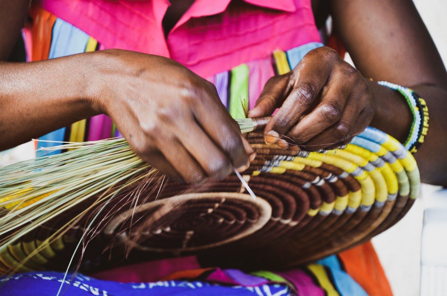 Close-up of a woman's hands as she weaves a traditional Rwandan peace basket