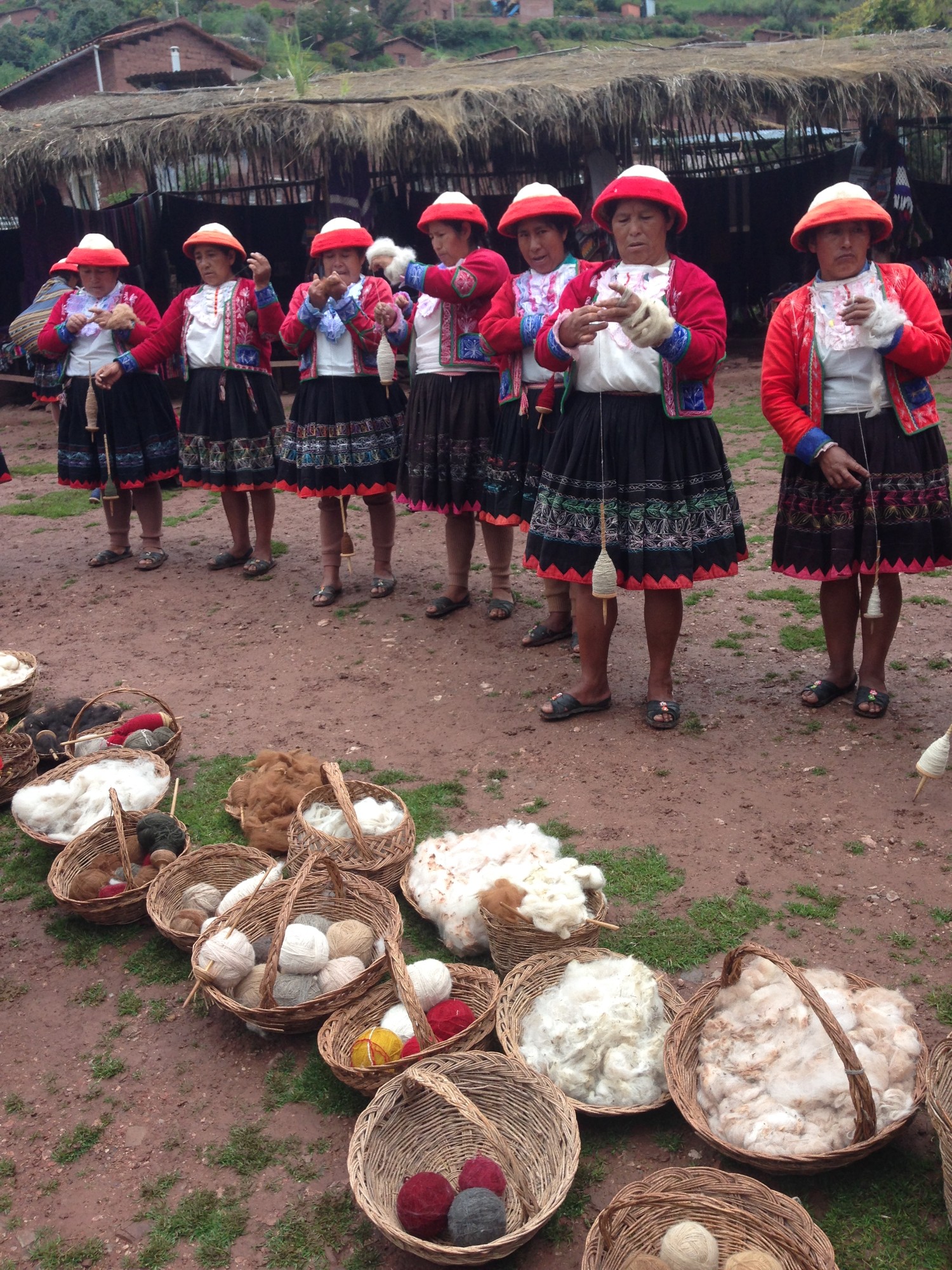 Women of Ccaccaccollo standing together and winding wool, wearing traditional dress