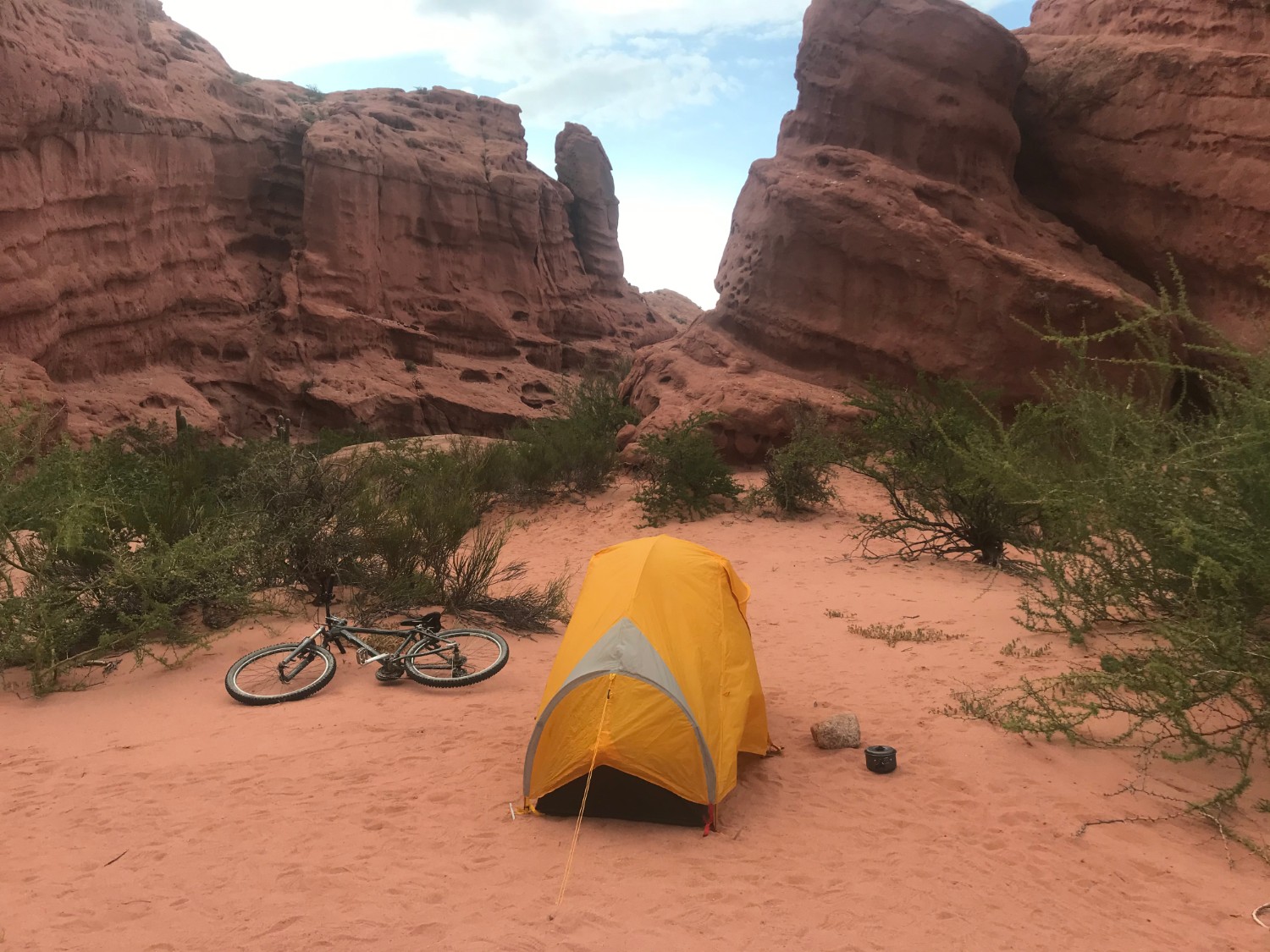 Solo camping in Argentina - image of a solo tent and a bicycle with pillar formations behind