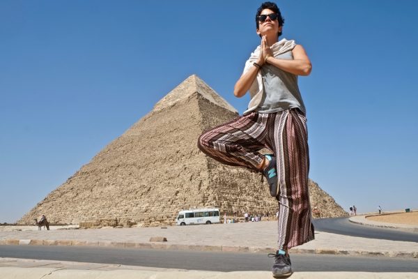 Woman doing a tree pose in front of the Pyramids of Giza