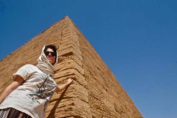 Woman with headscarf standing against a pyramid