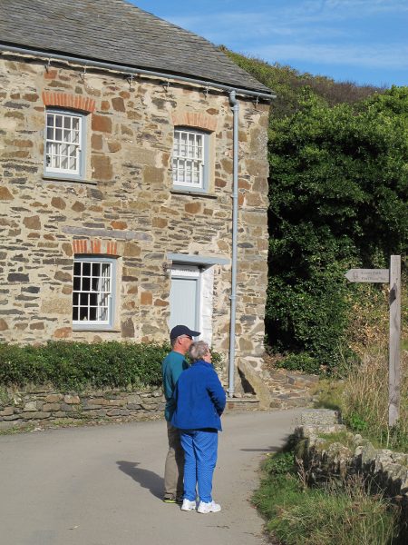 Two elderly people standing next to an old cottage home