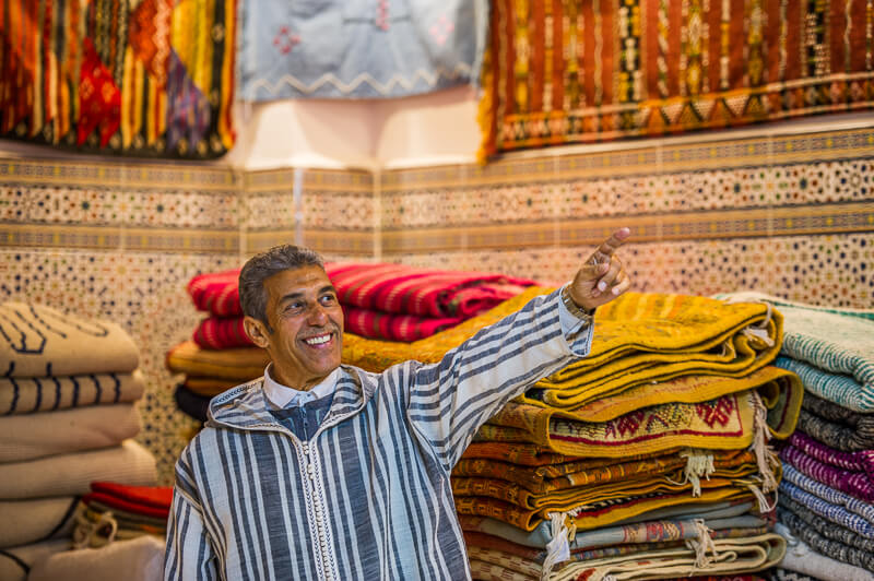 Man pointing at traditional Moroccan woven rugs