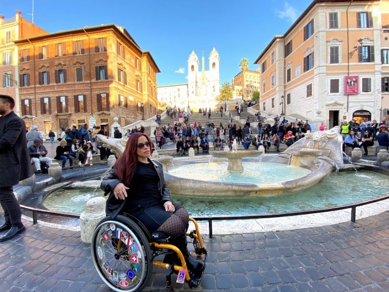 Laurita Tellado poses in her wheelchair in front of the Spanish Steps in Rome on a clear, sunny day