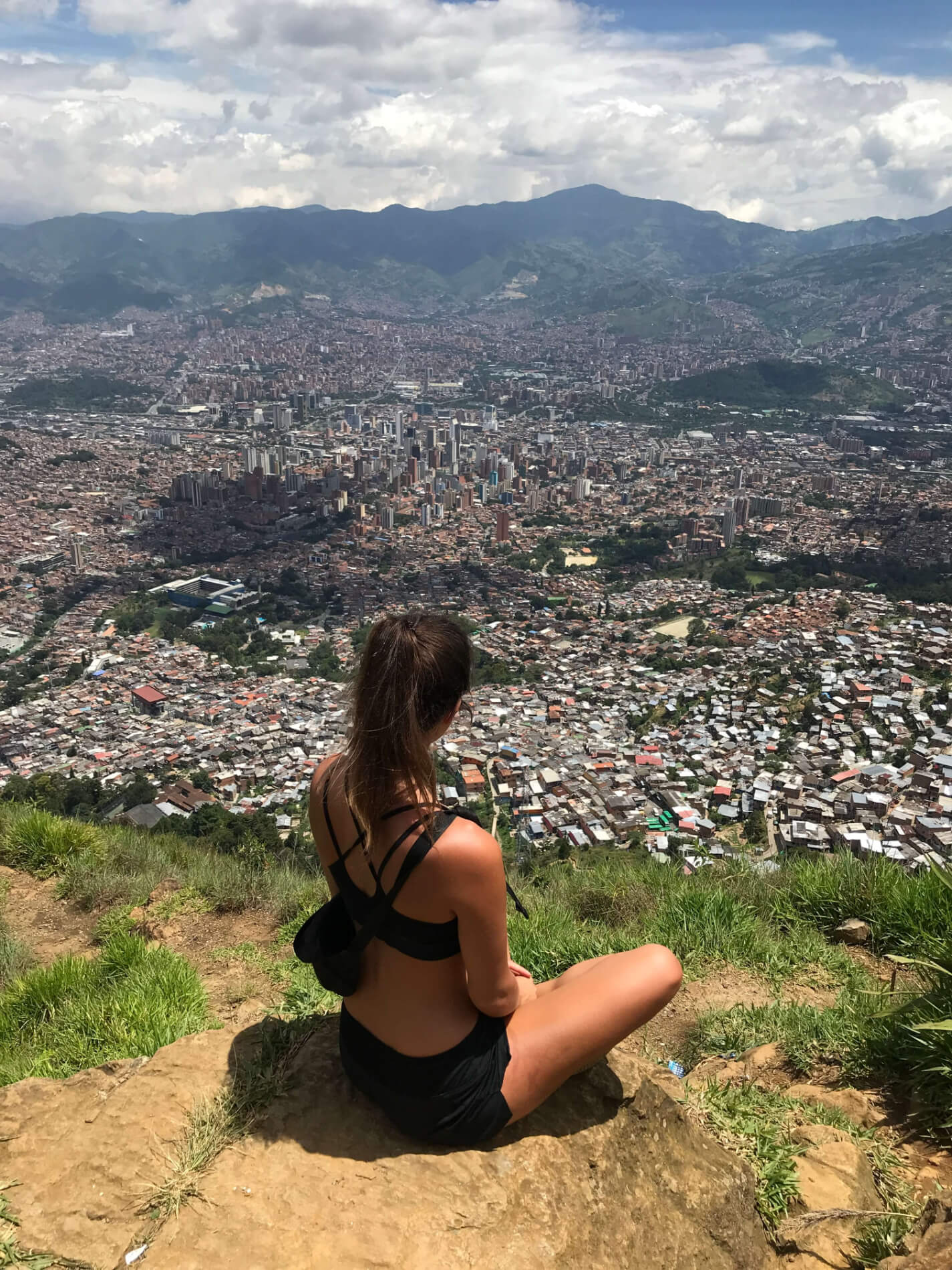 Helene Doetsch image from behind as she sits atop a hill overlooking a city