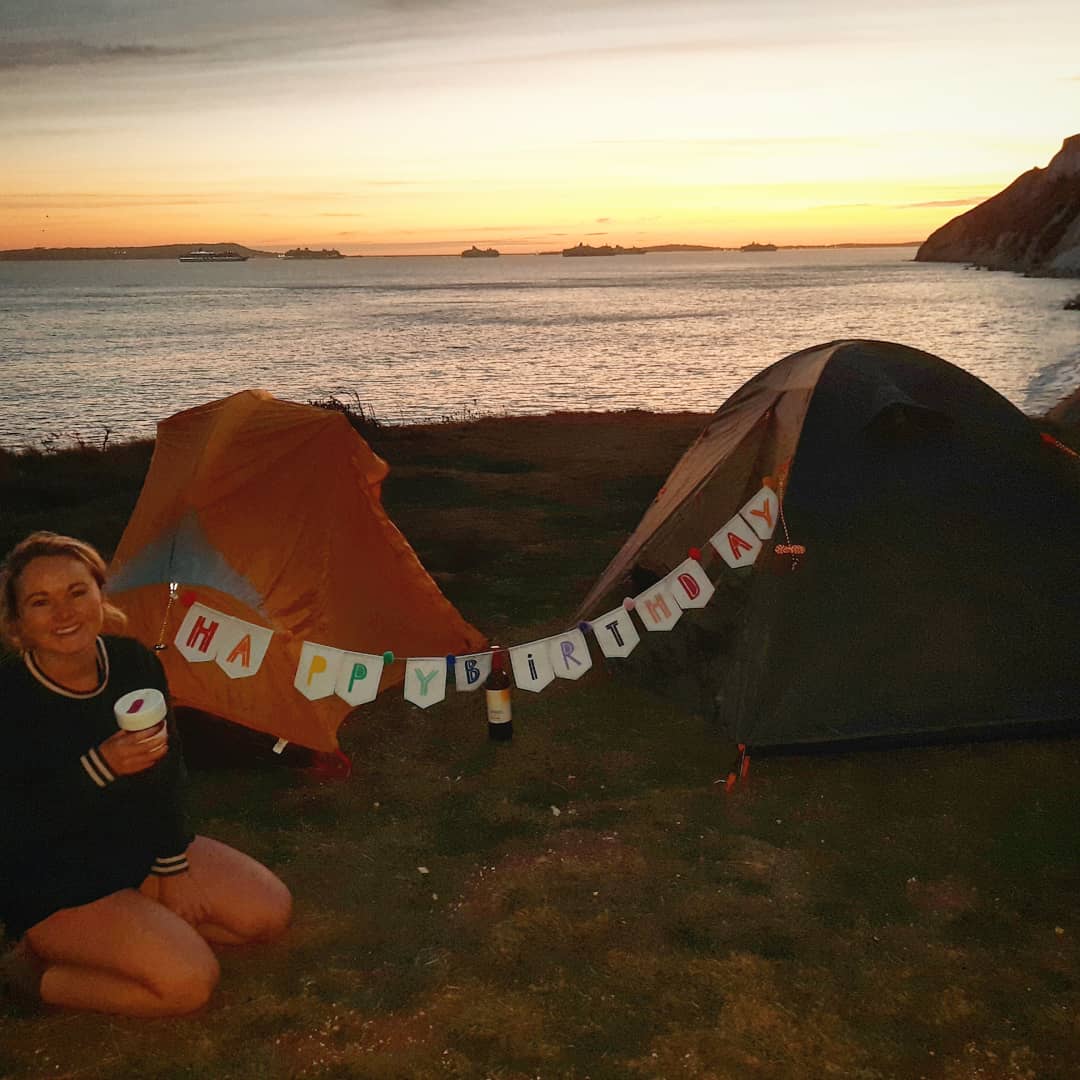 Anna Richards wild camping in the UK with a Happy Birthday sign strung across the tent
