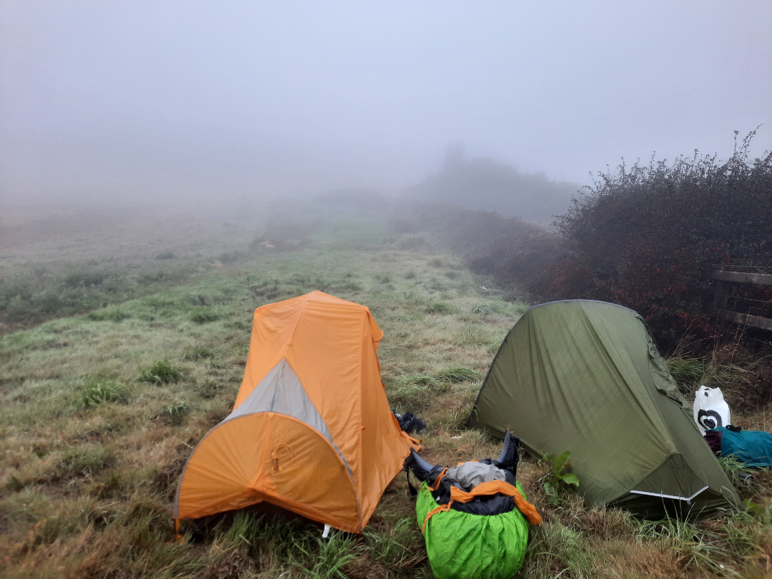 Wild camping in the UK - tents on a grassy field in the fog