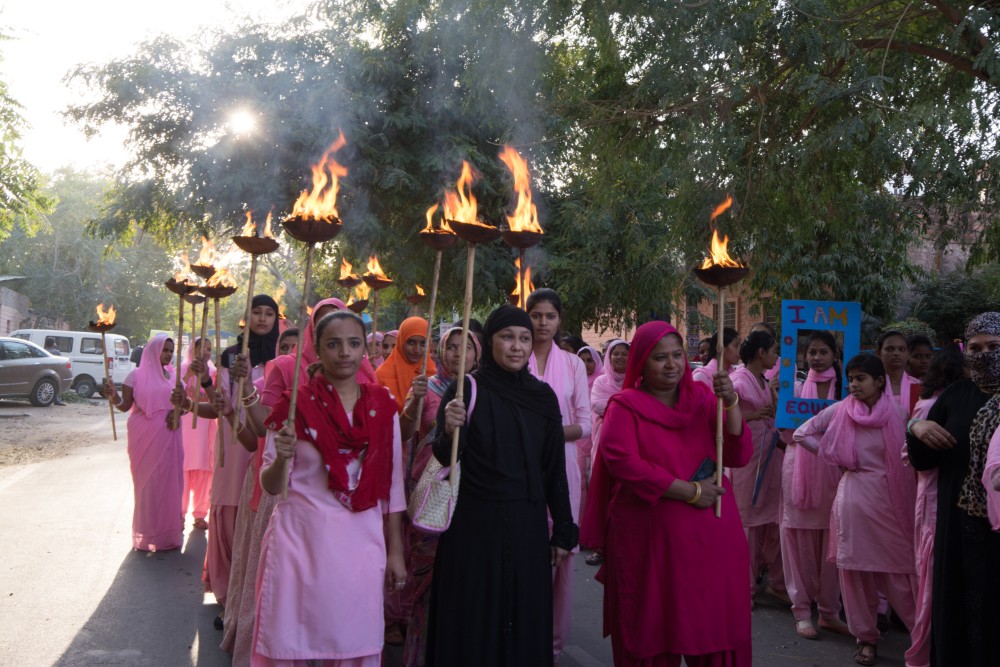 Women of Rajasthan in pink saris carrying torches for women's rights