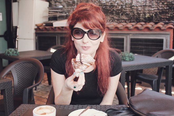 Red-headed woman eating a breakfast pastry